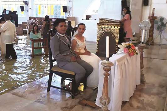 Bride Jobel Delos Angeles, 24, and her groom during their wedding amidst a flooded church in Hagonoy town, Bulacan town, north of Manila, yesterday.