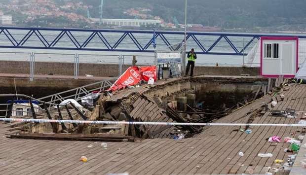 A police investigator inspects the seafront platform in Vigo after a section of a wooden promenade suddenly collapsed with people watching a rap artist just before midnight on Sunday.