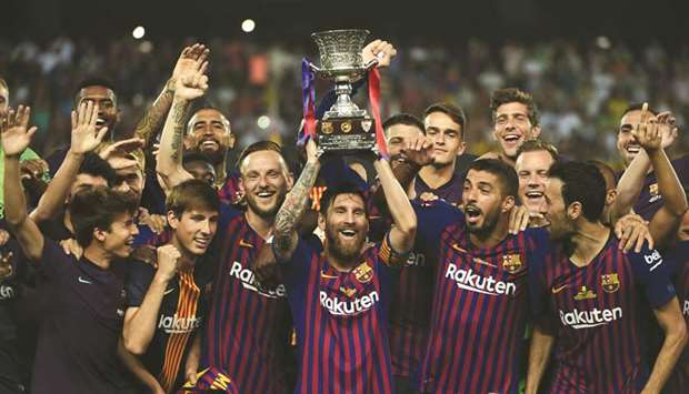 Barcelona captain Lionel Messi (centre) lifts the trophy as he celebrates with his teammates after winning the Spanish Super Cup at Ibn Batouta Stadium in the Moroccan city of Tangiers on Sunday night. Barcelona defeated Sevilla 2-1. (AFP)