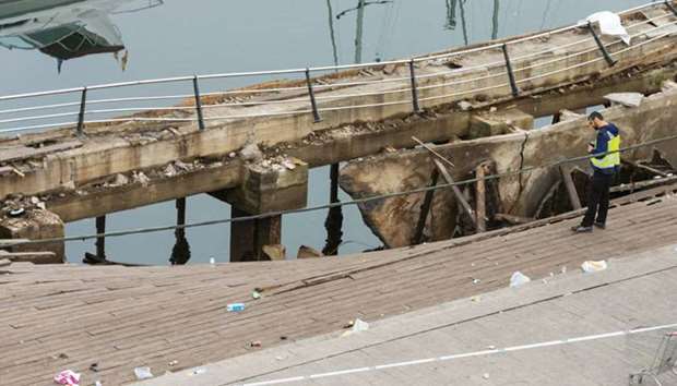 A police investigator inspects the collapsed seafront platform in Vigo yesterday.