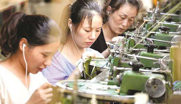 Employees work on a production line of clothes for export at a factory in Xiayi county, Henan province. Key economic readings released yesterday in China showed investment slumping to a record low for the first seven months of the year as retail sales slowed, pointing to weakness in the worldu2019s second largest economy.