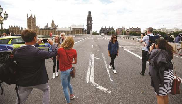 Tourists pose for pictures at a police cordon on Westminster Bridge, after a car crashed outside the Houses of Parliament in Westminster, London.