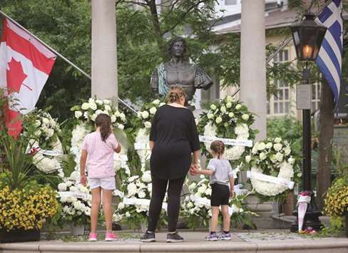 A Canadian flag hangs above memorial wreaths at Alexander the Great Parkette, the scene of a mass shooting on Danforth Avenue in Toronto on July 24.