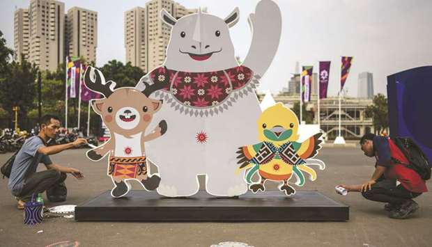 Workers put finishes on an installation showing mascots Atung (left), Kaka (centre), and Bhin Bhin (right) ahead of the 2018 Asian Games in Jakarta yesterday. (AFP)