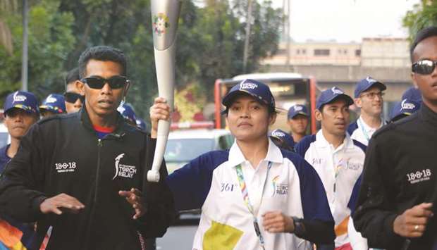 Indonesiau2019s former taekwondo athlete Ade Novriza (C) carries the 2018 Asian Games torch in Jakarta yesterday. (AFP)