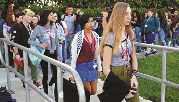 Students wait to cross a street to enter classes yesterday at Marjory Stoneman Douglas High School in Parkland, Florida.
