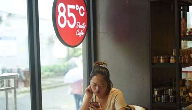 A woman looks at her mobile phone at a 85C Bakery Cafe in Hangzhou in China's eastern Zhejiang province on Thursday.