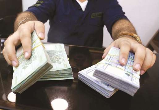 A money exchange vendor displays Lebanese pound banknotes at his shop in Beirut yesterday. Lebanese banks are pulling out the stops to bring in dollars as the country strives to preserve a two-decade old currency peg, offering high returns to customers willing to change their hard currency into long-term Lebanese pound deposits.
