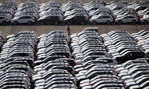 A worker is seen among newly manufactured cars awaiting export at a port in Yokohama. Japanu2019s exports to the US fell 5.2%, a second straight decline, paced by a 12.1% fall in car shipments.