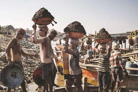 Migrant workers unload sand from Indian owned boats on the Thane River near Ghodbunder Village in Maharashtra.