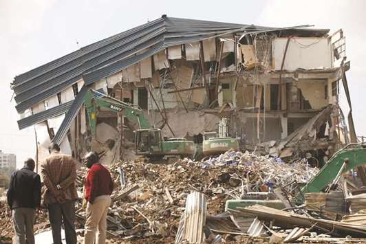 People watch as heavy machinery demolishes the UKAY Mall in Westlands, Nairobi.