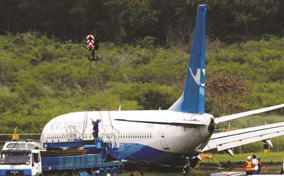 Workers try to remove a Xiamen Air Boeing 737-800 from the tarmac after it skidded off at the runway of Ninoy Aquino International airport in Paranaque, Metro Manila.