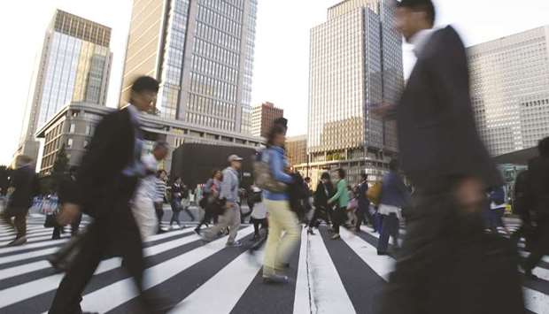 People cross a street at Tokyou2019s business district. Japanese business confidence is at its highest in seven months in August thanks to a firm global economy, a Reuters poll showed yesterday.