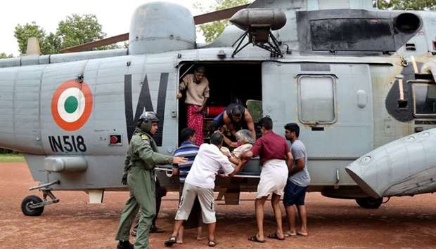 People help a woman disembark from an Indian Navy helicopter at a relief camp after being rescued from a flooded area in the southern state of Kerala