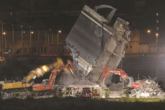Rescuers use heavy machinery as they work among the rubble of the Morandi motorway bridge, days after a section collapsed in Genoa.