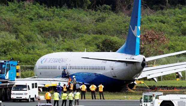 Workers trying to remove the Xiamen Air Boeing 737-800 from the tarmac after it skidded off at the runway of Ninoy Aquino International airport in Paranaque, Manila