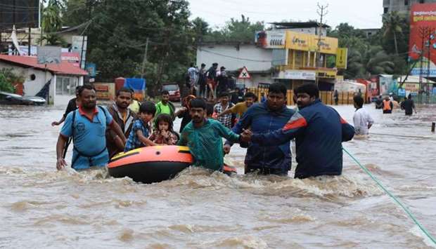Indian volunteers and rescue personal evacuate local residents in a boat in a residential area at Aluva in Ernakulam district
