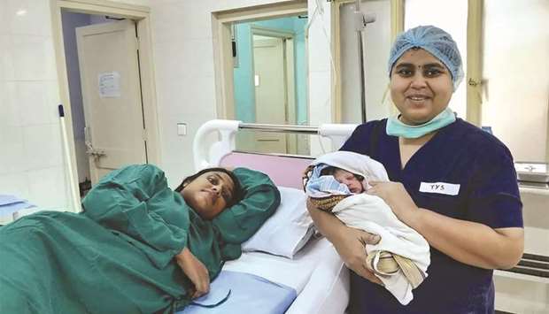 A nurse holds a newborn boy next to the mother Sajita Jabeel in a hospital in Kochi, after she was rescued from a roof in a flood affected area of Kochi.