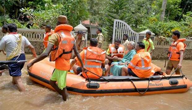 Kerala and Tamil Nadu Fire Force personnel ferry children and the elderly in a dinghy through flood waters during a rescue operation in Annamanada village, Thrissur district, on Sunday.