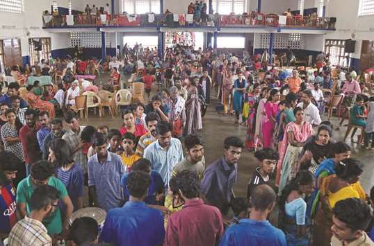 Flood victims wait for food inside a college auditorium, which has been converted into a temporary relief camp, in Kochi, yesterday.