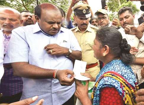 Karnataka Chief Minister H D Kumaraswamy hands over a cheque to a woman from the flood-hit Kodagu district yesterday.