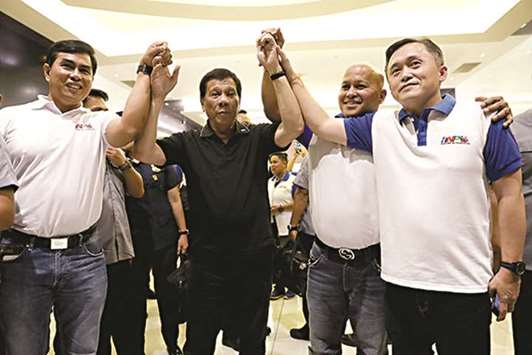 President Rodrigo Duterte raises the hands of Bureau of Corrections chief Ronald Dela Rosa (second from right) and his top aide, Christopher Lawrence u2018Bongu2019 Go (right) on the sidelines of a convention in Davao City.