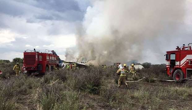 Durango's Civil Protection showing firemen working as smoke billows from the wreckage of a plane that crashed with 97 passengers and four crew on board on take off at the airport of Durango