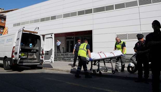 The body of a man who tried to attack a police station is wheeled into a van in Cornella