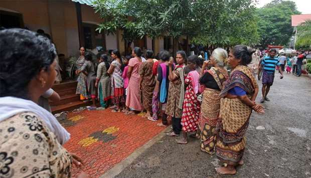 Flood-affected women wait in a queue to receive relief material at a camp in Chengannur