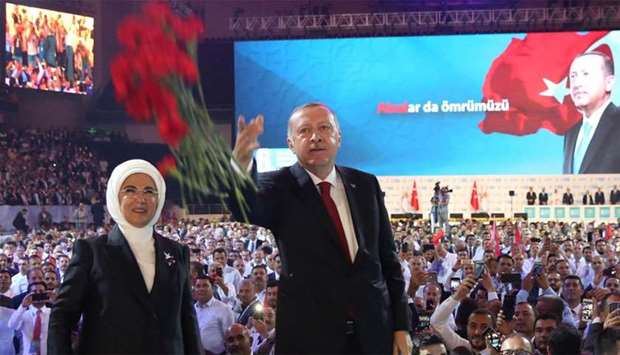 Turkish President Recep Tayyip Erdogan (R) gestures as he and his wife Emine Erdogan (L) greet supporters
