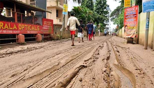 People walk along a muddy road in Kochi following widespread flooding in the south Indian state of Kerala on Monday.