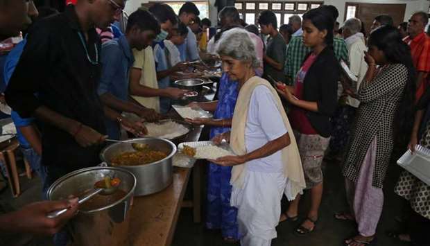 A flood-affected woman receives food inside a college auditorium, which has been converted into a temporary relief camp, in Kochi in the southern state of Kerala. Reuters