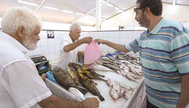 A Libyan man buys fish from a fishmonger at the market in Tripoli.