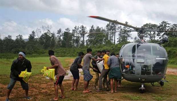 Flood victims unload food and relief material from an Indian Air force helicopter at Nelliyampathy village in Kerala on Tuesday.