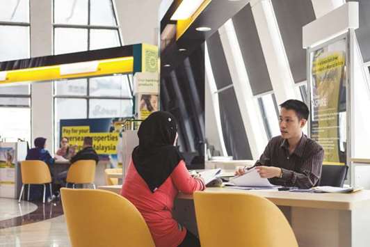 An employee serves a customer inside the Malayan Banking Bhd (Maybank) branch at the companyu2019s headquarters in Kuala Lumpur (file). The Islamic  banking assets and financial products in Asia are much larger than those in Europe and North America, largely due to the Malaysian Islamic finance  marketplace, which makes the country a global leader in Islamic financial services, holding more than a 10%-share of the global Islamic banking assets.