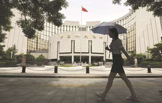 A pedestrian walks past the Peopleu2019s Bank of China building in Beijing. The PBoC said it will u201ceffectively easeu201d companiesu2019 financing problems and improve co-ordination with other agencies to ensure monetary policy measures are being transmitted into the broader economy.