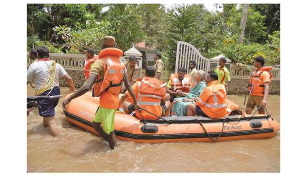 Kerala and Tamil Nadu Fire Force personnel ferry an elderly in a dinghy through flood waters during a rescue operation in Annamanada village in Thrissur District, in Kerala, on August 19.