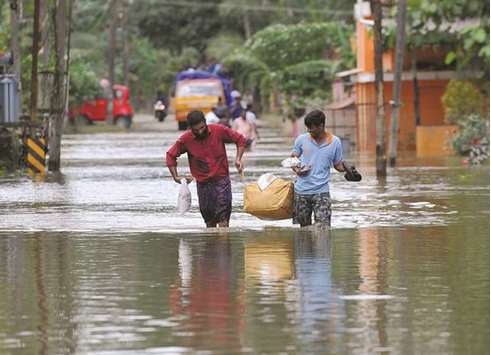 Men carry food and water aid distributed to those stranded by floods in Pandanad in Alappuzha district.