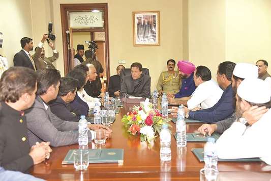 This handout photograph released by the Press Information Department (PID) on August 18, shows Prime Minister Imran Khan with members of the 1992 Cricket world cup team and former Indian cricketer Navjot Singh Sidhu (top right) in Islamabad.
