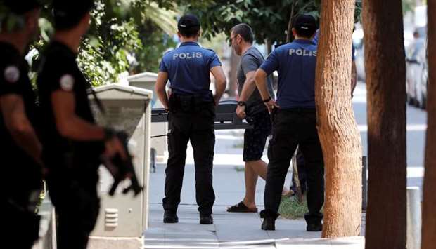 A man carries treadmill as police officers patrol outside the home of US pastor Andrew Brunson in Izmir, Turkey on Monday.