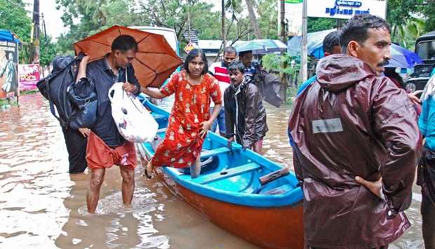 Fishermen and rescue personnel evacuate local residents in a boat in a residential area at Kozhikode, in the Indian state of Kerala