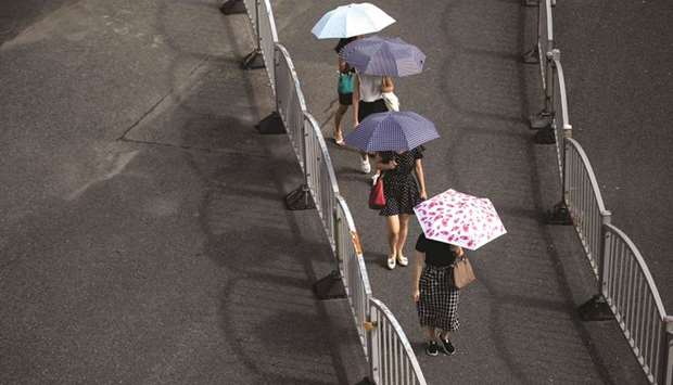 Commuters walk to work in the financial district of Pudong in Shanghai yesterday. Chinau2019s momentum has stalled as policy makers curb risky lending and the trade dispute with the US begins to bite, prompting policy makers to shift gears to signal a willingness to support activity. Economists also see a slowdown in Japan.