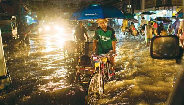 A man rides a tri-shaw along a flooded road in Yangon yesterday.