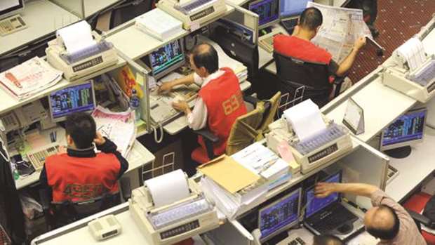 Traders are seen at the Hong Kong Stock Exchange. The Hang Seng Index fell 0.5% to 27,790.46 points yesterday.