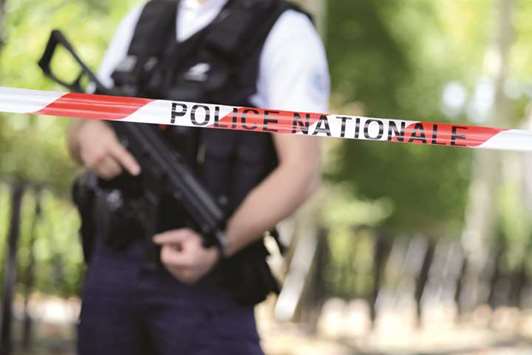 A police officer guards a cordoned-off road in Trappes, southwest of Paris, yesterday following a knife attack.