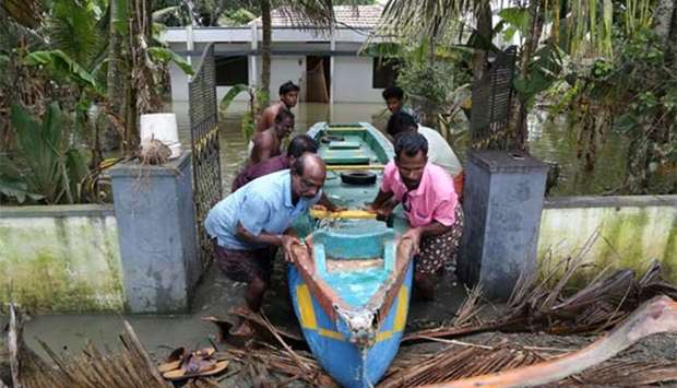People push a boat through the gate of a flooded house at Kuttanad in Alleppey district in Kerala on Friday.