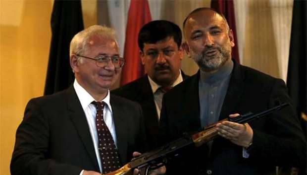 Russia's ambassador to Afghanistan Alexander Mantytskiy (left) hands over an AK-47 to Afghan national security adviser Hanif Atmar (right) after a conference in Kabul on February 24, 2016. File picture