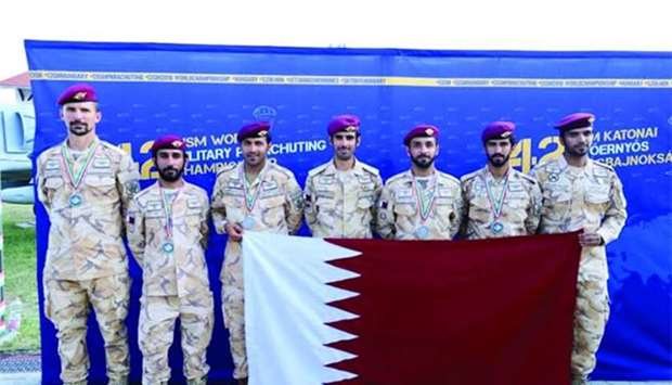 Team members hold the Qatari flag.