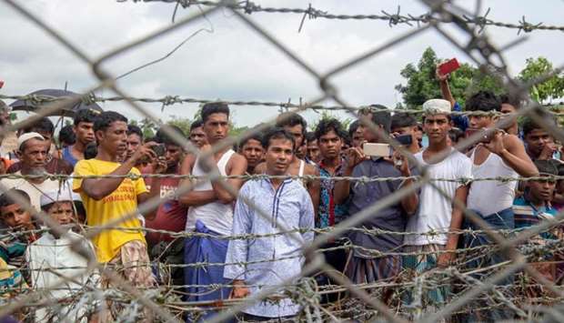 Rohingya refugees gather near the fence in the ,no man's land, zone between Myanmar and Bangladesh border as seen from Maungdaw, Rakhine state during a government-organized visit for journalists yesterday AFP