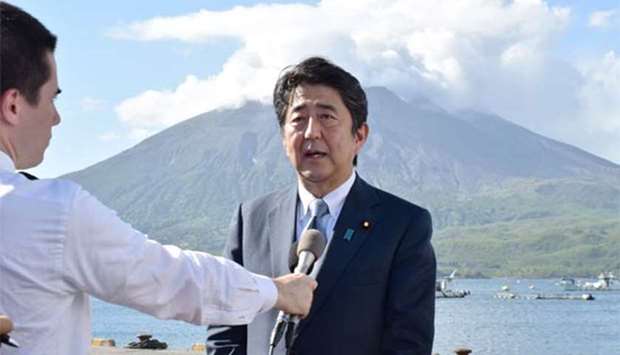Japan's Prime Minister Shinzo Abe speaks to the media in front of Mount Sakurajima volcano while on tour to Tarumizu, Kagoshima prefecture on Sunday.